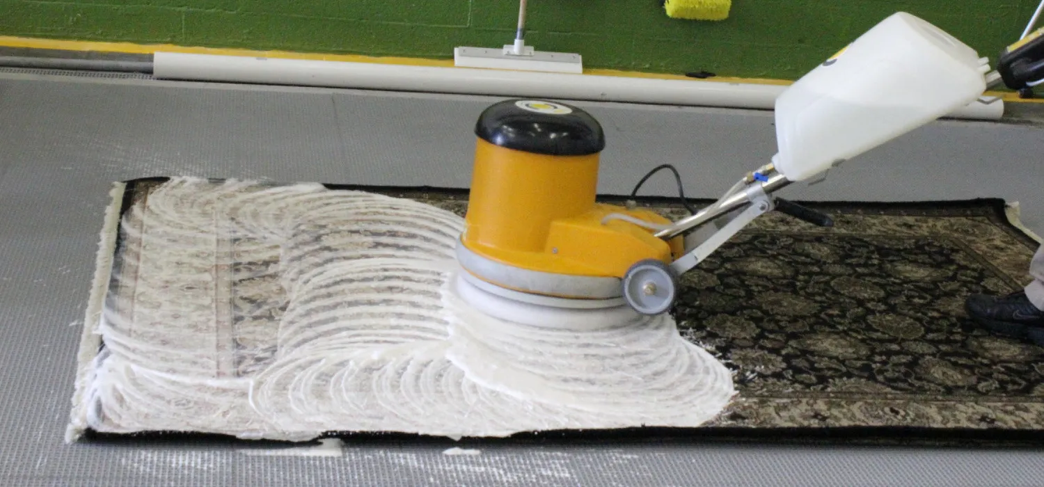 M&aacute;quina rotativa lavando un tapete oriental sobre el piso de la planta