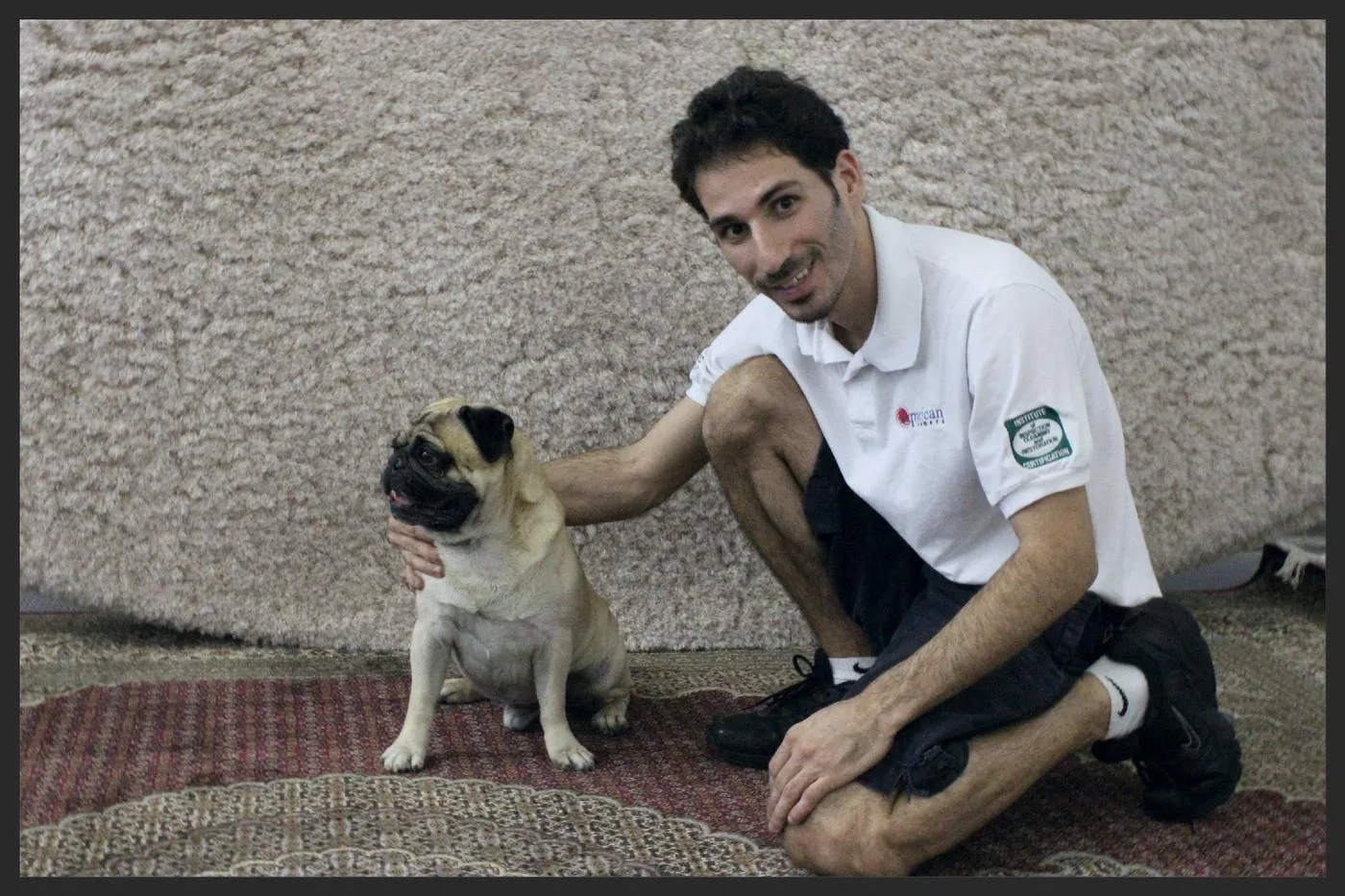 T&eacute;cnico de la empresa en la planta de lavado junto a un pug sobre un tapete oriental